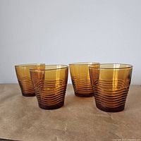Four amber juice glasses in a group showing wave texture pattern and amber glass color.