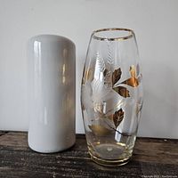Two vintage vases shown together: gray ceramic cylindrical vase and clear etched glass vase with gold leaf pattern