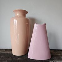 Pair of vintage 80s ceramic vases in peach and pink colors side by side on wooden surface with neutral wall background