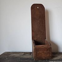 Front view of vintage wooden hanging box showing overall structure with tall back panel and open top box portion.
