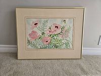 Front view of framed watercolor painting showing pink flowers and greenery, framed in gold with double matting.
