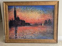 Front view of impressionist-style framed painting showing sunset colors and silhouetted buildings over water.
