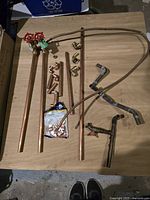 Photo showing variety of copper plumbing parts laid out on a table, including pipes, valves with red handles, elbows, tees, and smaller fittings.