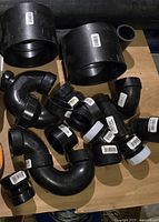 Photo showing a variety of black ABS pipe elbows and couplers with barcode labels.