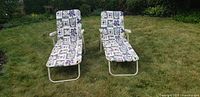 Front view of two outdoor lounge chairs with patterned cushions on a grassy lawn.