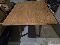 Full view of antique wooden extendable table showing the table top with attached fold-out leaves extended.