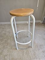 Round wooden seat and white metal stool frame, showing side and leg construction