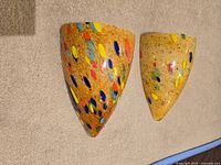 Front view of two glass sconce lights showing beige base with multicolor speckles.