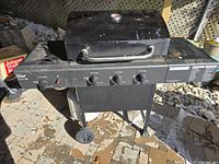 Full view of the black Master Chef propane gas BBQ grill with four control knobs and mounted on wheels.