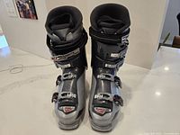 Front view of pair of Nordica Cruise ski boots, size 28.5, showing four buckle fasteners and power strap, black and silver with red highlights.