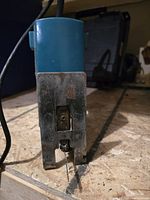 Front view of Makita jig saw blade and base showing metal parts and worn marks, on a wooden surface.