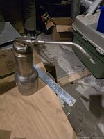 Metal oil pump with hand lever on a wooden surface in a cluttered background