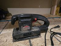 Front side view showing Jobmate brand label, main handle with red power button, and power cord attached