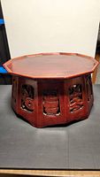 Full view of octagonal wooden tea table with carved panels around the sides and flat top surface.
