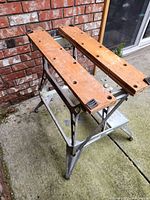 Folding Black and Decker work bench assembled showing wooden top surfaces with multiple holes and silver metal frame.
