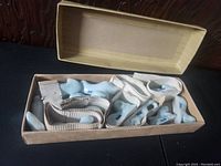 Cardboard box with fabric strips containing ceramic zodiac animal figurines inside.