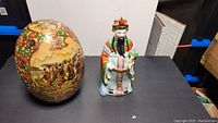 Photo of both the large decorated egg and spiritual figure statue on black surface