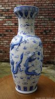 Front view of large white vase with three-dimensional blue dragons and decorative blue patterns