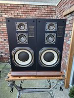 Pair of vintage Fisher STC 861 speakers on wooden table outdoors, showing front panel drivers and branding