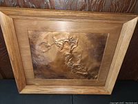 Frontal view of the vintage embossed copper artwork showing two birds on a plum tree branch with wooden frame.