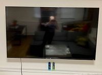 Front view of mounted TCL Roku TV with two remotes placed below