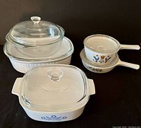 Photo showing the five Corningware cookware pieces with lids, showcasing different floral patterns and clear glass lids.