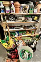 Full shelf and floor display of garden supplies including soil bags, terra cotta pots, and garden tools.