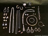 Overview photo showing a collection of gold-tone jewelry items including earrings, bracelets, necklaces, and a tie clip.