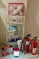 Full view of lot on storage cart including alarms, doorbell, fire extinguishers, first aid kit, cleaning supplies, water filters, emergency light.