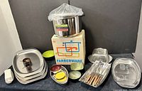 Photo of entire collection showing stock pot with box, serving trays, covered dishes, fondue forks, enameled bowls and coasters, teak spice bowls, and glass butter dish covered with plastic.