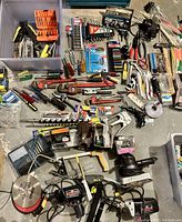 Overview of all tools spread out on floor including hand tools, power tools, drill bits, wrenches, and organizers
