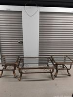 Three-piece glass top metal coffee table set including one large rectangular coffee table and two smaller square side tables on bronze-colored metal frames.