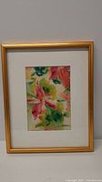 Framed watercolor flower painting with a gold frame and white matting, shown from a distance.