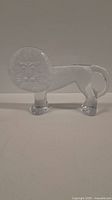 Full side view of the entire glass lion sculpture showing the clear glass body and textured circular mane.