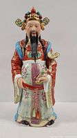 Front view of Japanese ceramic sculpture of a male figure in traditional outfit, showing facial features, headdress, and front garment details