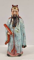 Front view showing detailed facial features, robe decorations, and scroll in hand