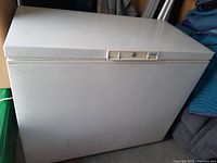 Closed chest freezer angled view showing white exterior and top lid with latch.