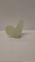 Side view of the pale green jade chicken figurine showing the tail feathers and comb on head.