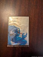 Front side of a holographic trading card showing blue Venom character on silver foil background.