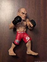 Front view of Randy Couture MMA figure showing fighting stance, facial details, and red shorts with branding.