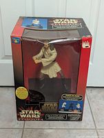 Front view of Star Wars Episode 1 Qui-Gon Jinn talking bank figure in original box with visible wear damage on top edges.