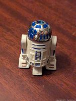 Front-facing view of small R2-D2 figure showing detailed painted dome and white body with blue accents.