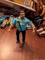 Front view of the Big Boss Man figure in police uniform on wooden surface, highlighting details of uniform and face.