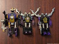 Photo of the three Transformers Insecticons laid out side by side on a wooden surface showing size, condition, and included accessories.