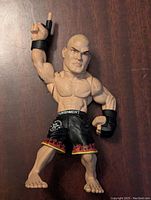 Front view of the Tito Ortiz UFC action figure showing muscular build, black flame shorts, and raised right arm.