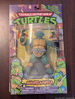 Front of unopened Michelangelo TMNT action figure in blister pack showing figure and accessories with colorful TMNT-themed packaging.