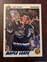 Front side of the Felix Potvin signed rookie card showing him in goalie gear holding a trophy with his signature.