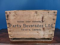 Front view showing the lettering 'Bottled Under Authority of Party Beverages Ltd., Toronto, Canada.' on the wooden crate.