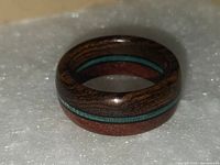 Close-up of the custom made ring showing three wood inlays and polished finish.