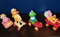 Four Muppet Babies 1987 McDonald's toys displayed side by side: Baby Miss Piggy, Baby Fozzie, Baby Kermit, and Baby Animal each mounted on different wheeled platforms.